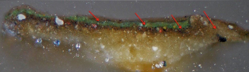 Magnified paint cross-section seen under a microscope, showing a thin green paint layer over brown and cream ground layers, with red arrows marking the layer boundary